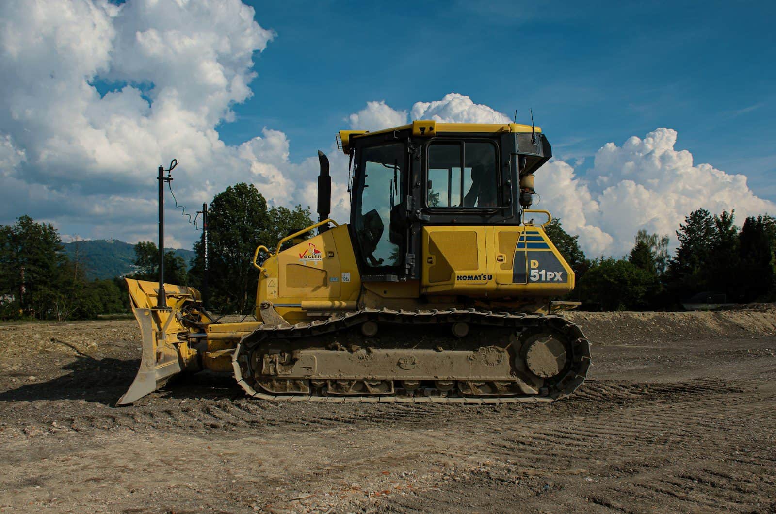 A tracked bulldozer with its blade lowered on a graded surface