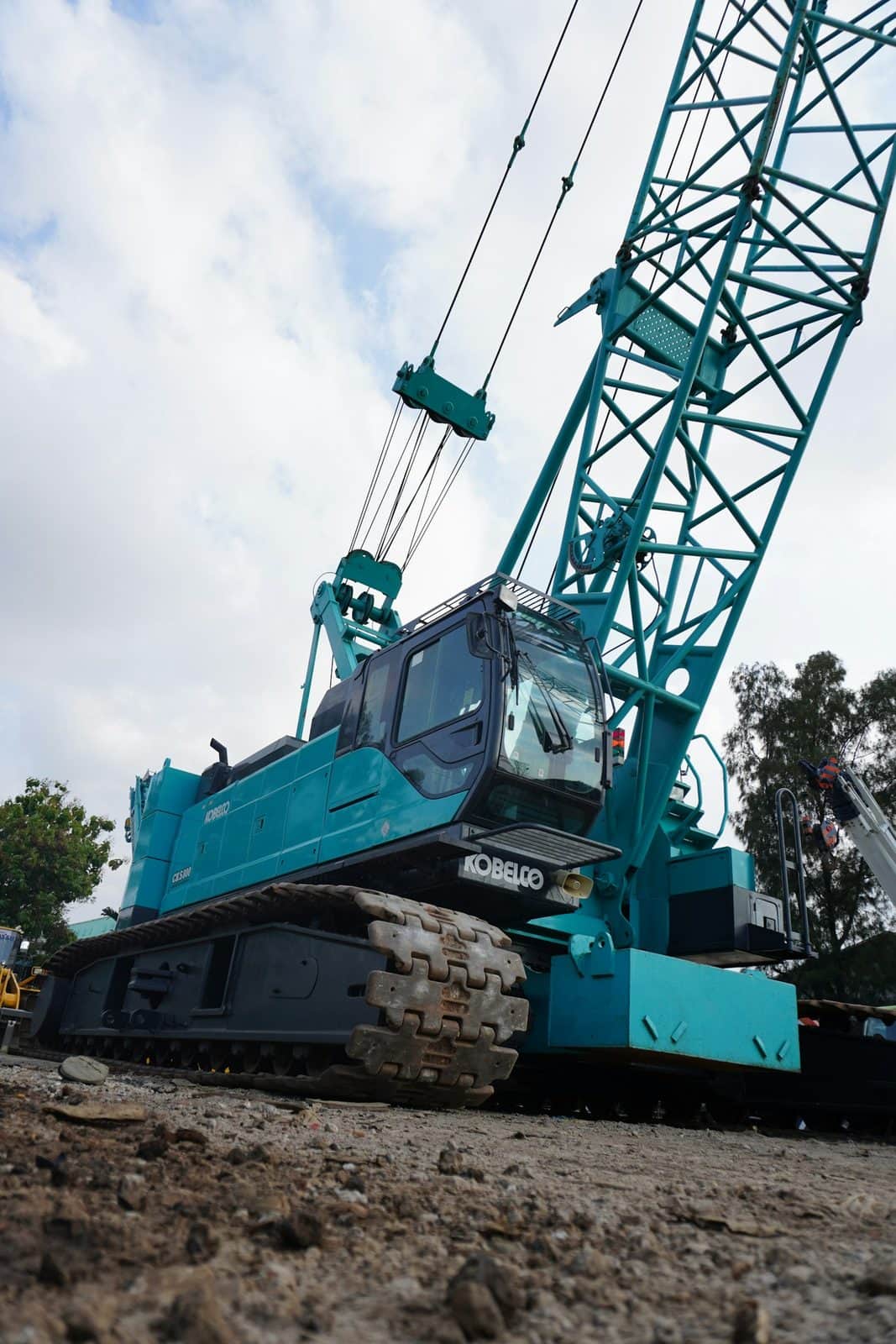 A crawler crane on tracks with its lattice boom raised at a site