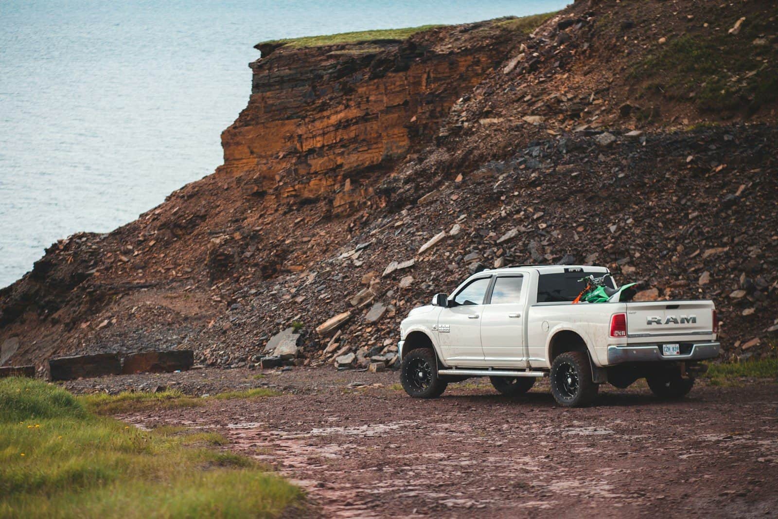 A crew-cab pickup parked at a rock face with equipment in the bed