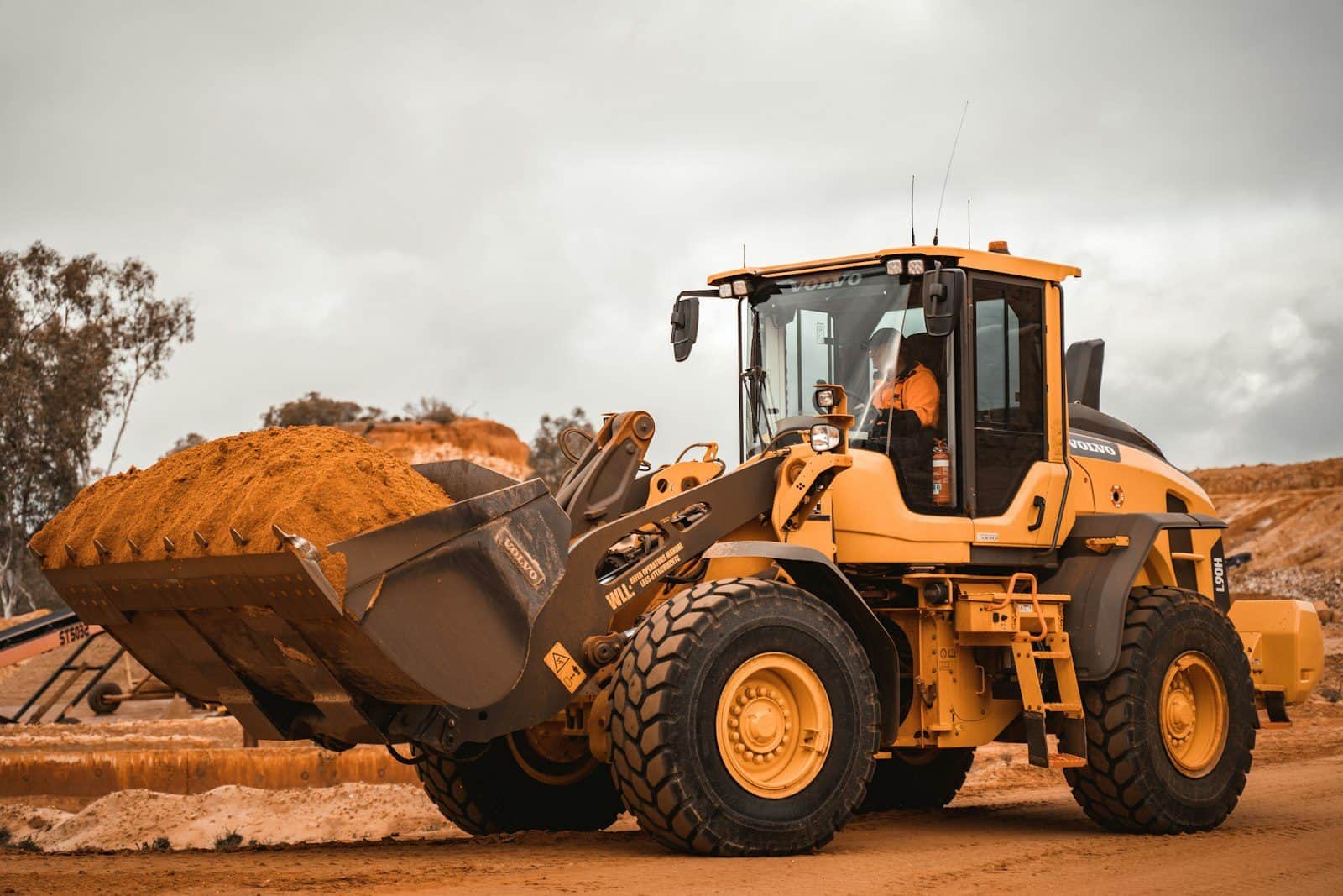 A wheel loader lifting a full bucket of earth