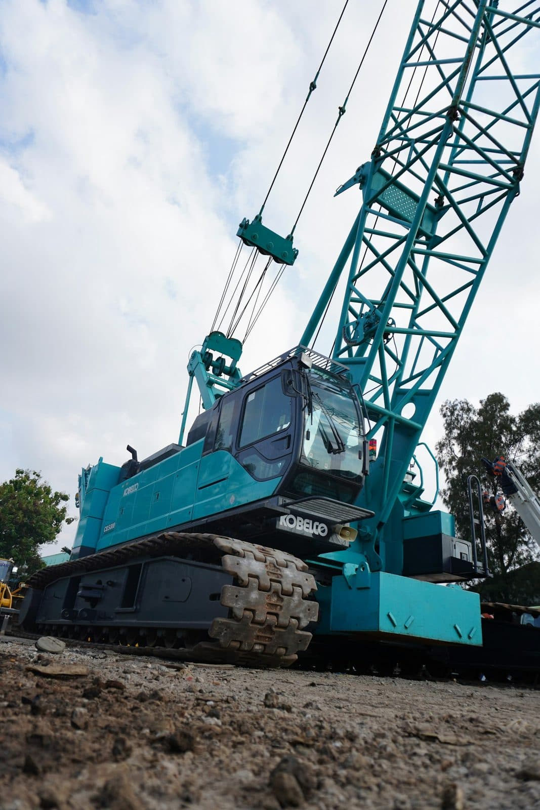 A crawler crane on tracks with its lattice boom raised at a site