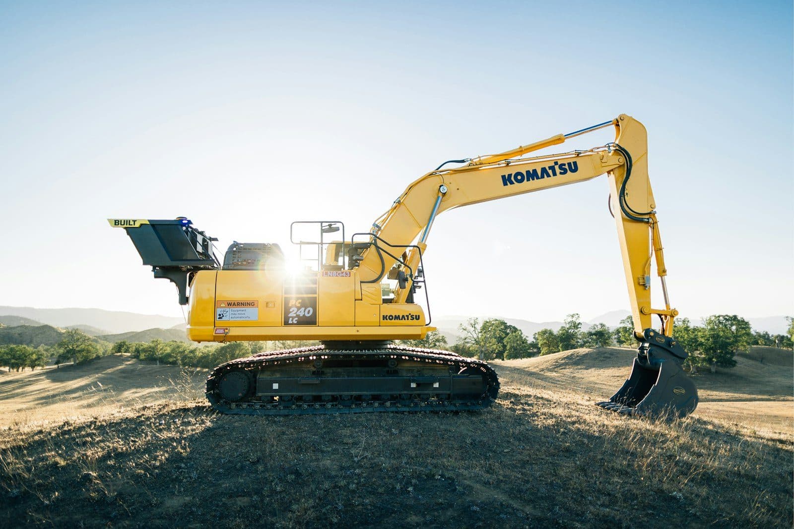 A tracked excavator with its bucket lowered on a working platform