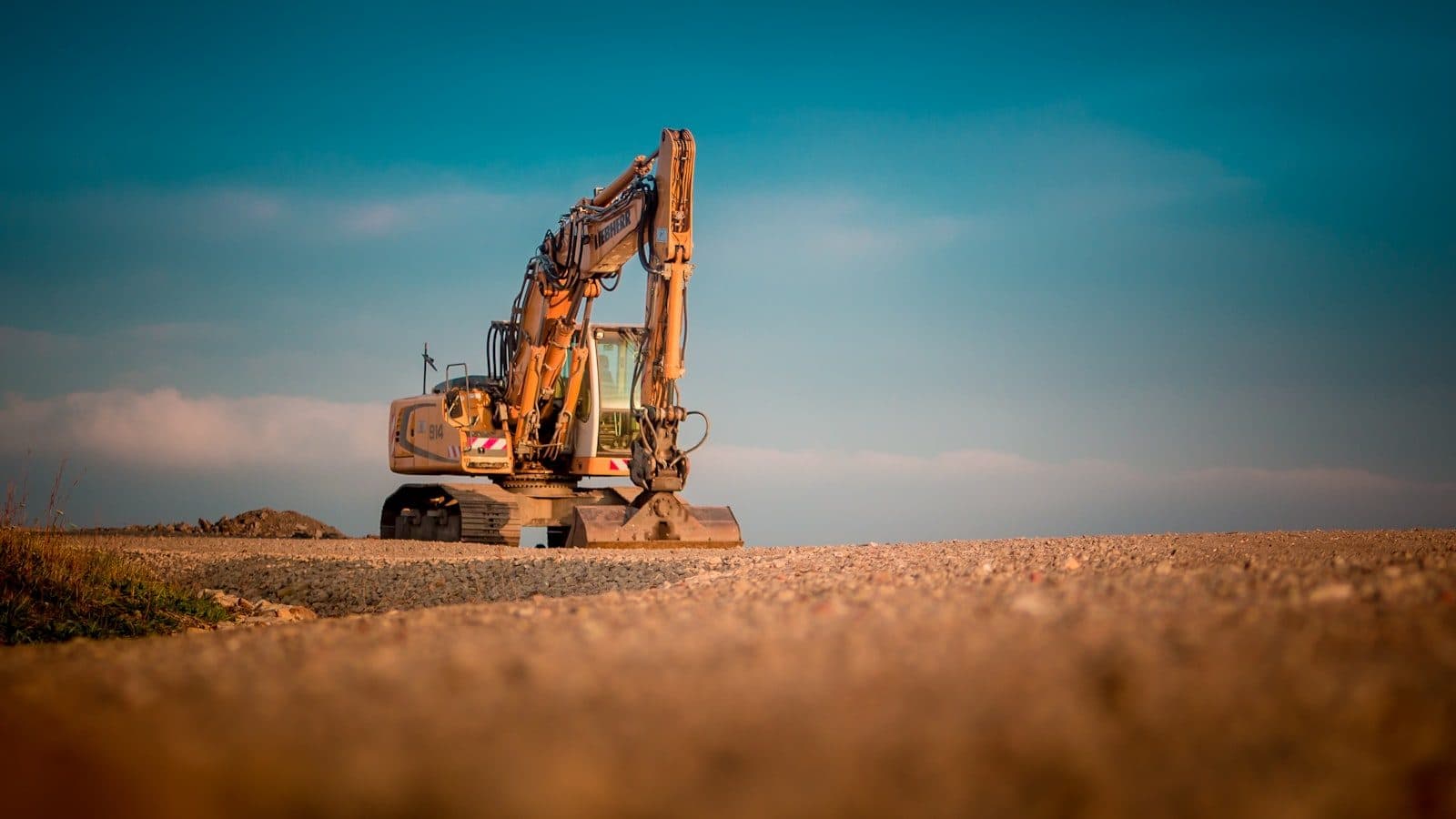 An excavator silhouetted against a dusk sky on a prepared site
