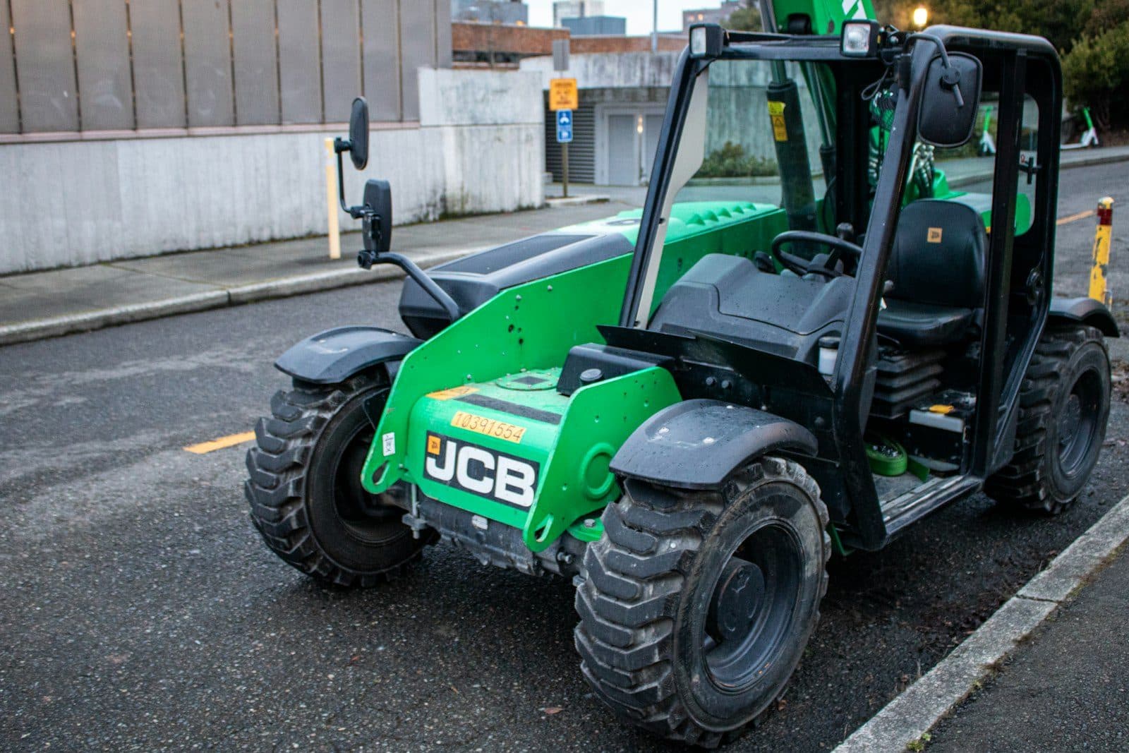 A compact telehandler with its telescopic boom lowered, parked kerbside
