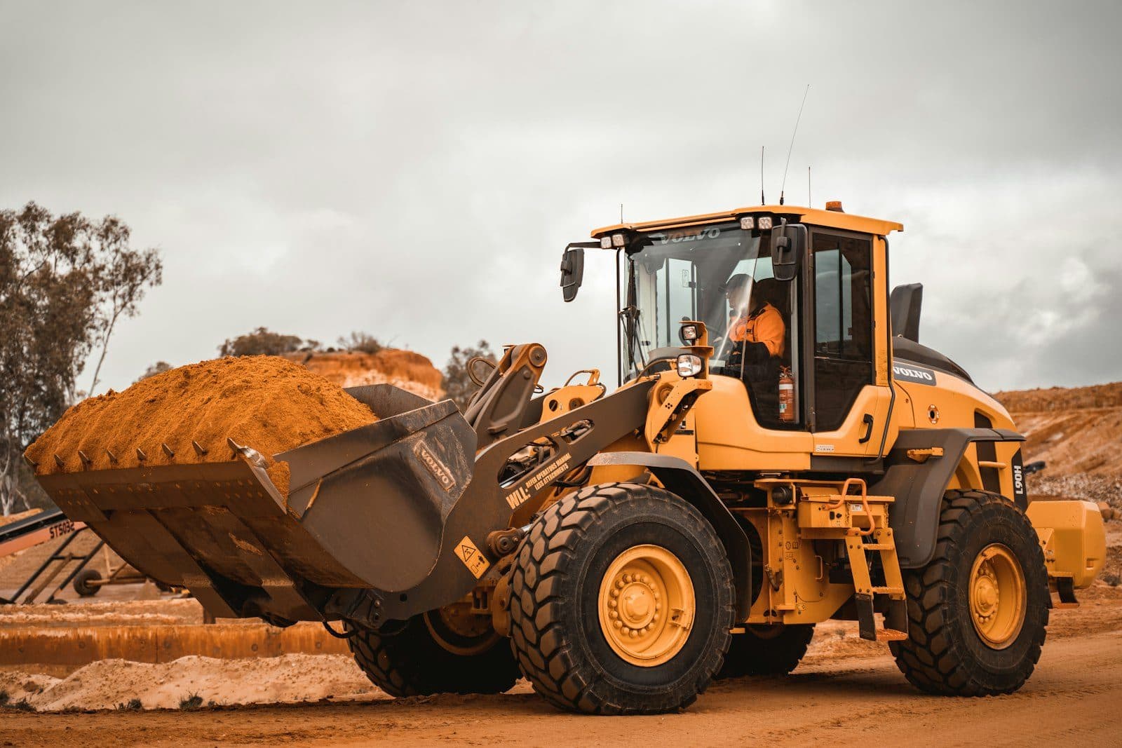 A wheel loader lifting a full bucket of earth